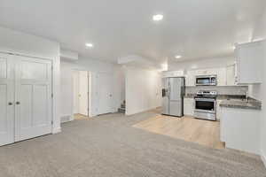 Kitchen with light carpet, sink, white cabinets, and appliances with stainless steel finishes