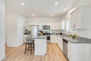 Kitchen with sink, a kitchen island, light hardwood / wood-style floors, and appliances with stainless steel finishes