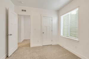 Unfurnished bedroom featuring light colored carpet and multiple windows