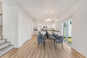 Dining area featuring sink, light hardwood / wood-style flooring, and an inviting chandelier