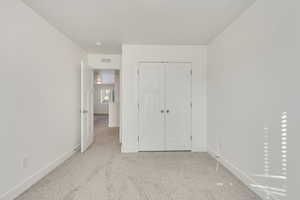 Unfurnished bedroom with a closet and light colored carpet