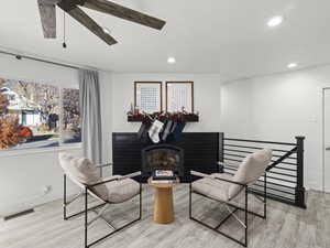 Sitting room featuring a wood stove, ceiling fan, and light hardwood / wood-style floors