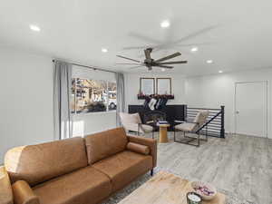 Living room featuring ceiling fan, light wood-type flooring, and a fireplace