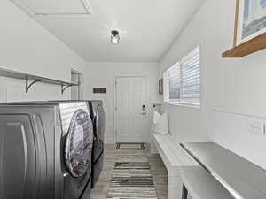 Laundry area with washer and clothes dryer and light wood-type flooring