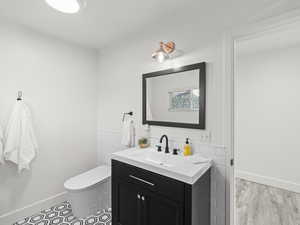 Bathroom with hardwood / wood-style floors, vanity, toilet, and tile walls