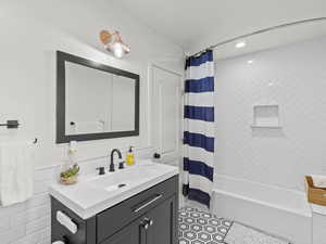 Bathroom with shower / bath combo with shower curtain, vanity, and tile patterned flooring