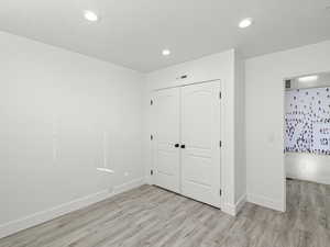 Unfurnished bedroom featuring light wood-type flooring and a closet