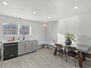 Kitchen featuring sink, pendant lighting, light hardwood / wood-style flooring, dishwasher, and gray cabinets