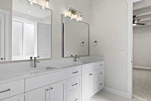 Bathroom with baseboards, a ceiling fan, double vanity, and marble finish flooring