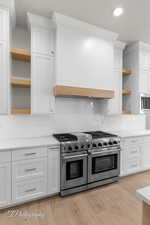 Kitchen featuring open shelves, stainless steel appliances, light countertops, tasteful backsplash, and recessed lighting