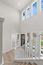 Stairs featuring wood finished floors, a towering ceiling, baseboards, and recessed lighting