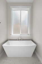 Full bathroom featuring marble finish floors, baseboards, and a freestanding bath