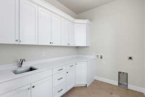Laundry room featuring cabinet space, hookup for an electric dryer, washer hookup, baseboards, and light tile patterned flooring