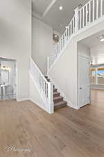 Staircase with a towering ceiling, wood finished floors, baseboards, and recessed lighting