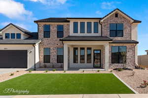 View of front of house featuring a front yard, driveway, stucco siding, and brick siding