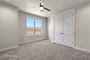 Unfurnished bedroom with carpet flooring, baseboards, a closet, and a textured ceiling