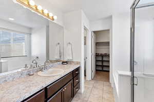 Bathroom featuring a shower with door, vanity, and tile patterned flooring