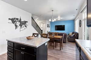 Kitchen with stainless steel dishwasher, decorative light fixtures, light hardwood / wood-style flooring, a chandelier, and a center island