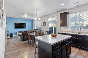 Kitchen featuring sink, a chandelier, decorative light fixtures, a kitchen island, and hardwood / wood-style flooring