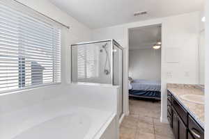 Bathroom with tile patterned flooring, vanity, ceiling fan, and independent shower and bath