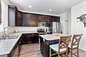 Kitchen featuring appliances with stainless steel finishes, a kitchen breakfast bar, sink, hardwood / wood-style flooring, and a kitchen island