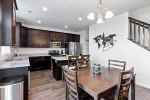 Kitchen with sink, hanging light fixtures, a kitchen island, wood-type flooring, and stainless steel appliances