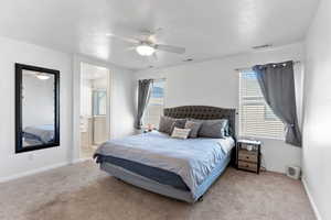 Carpeted bedroom with ensuite bathroom, ceiling fan, and a textured ceiling