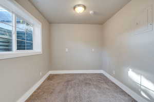 Carpeted spare room featuring a textured ceiling and electric panel