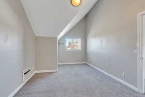 Additional living space featuring light colored carpet and lofted ceiling