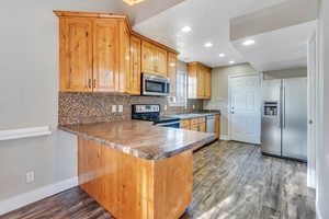 Kitchen with sink, kitchen peninsula, dark wood-type flooring, and appliances with stainless steel finishes