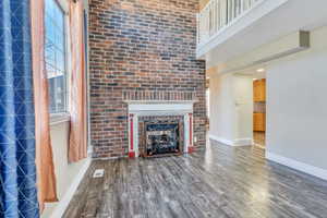 Unfurnished living room featuring a brick fireplace and hardwood / wood-style flooring