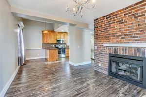 Unfurnished living room featuring a fireplace, dark hardwood / wood-style flooring, and a notable chandelier