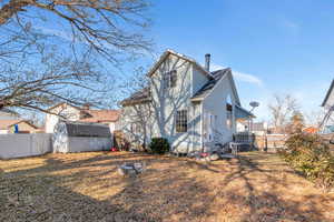 Rear view of property with a lawn and a storage shed