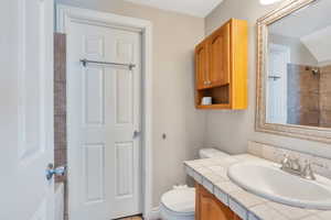 Bathroom with vanity, toilet, lofted ceiling, and a textured ceiling