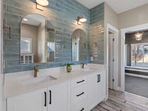 Bathroom featuring hardwood / wood-style flooring, vanity, backsplash, and tile walls