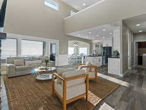 Living room featuring sink, a towering ceiling, dark wood-type flooring, and an inviting chandelier