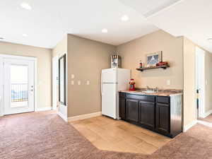 Kitchen featuring white refrigerator, light colored carpet, and sink