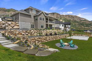 Rear view of house with a fire pit, a mountain view, a balcony, and a lawn