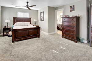 Carpeted bedroom featuring ensuite bathroom and ceiling fan