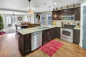 Kitchen with kitchen peninsula, appliances with stainless steel finishes, pendant lighting, and sink