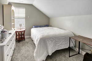 Carpeted bedroom with lofted ceiling and a textured ceiling