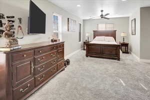 Bedroom with ceiling fan, light carpet, and multiple windows