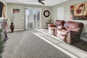 Carpeted living room featuring ceiling fan