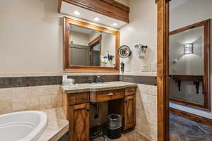 Bathroom featuring a washtub and vanity