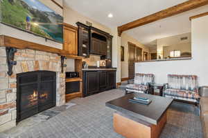 Living room featuring beam ceiling, sink, and a fireplace