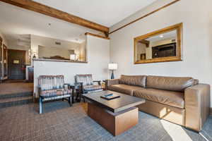 Living room featuring beam ceiling and dark carpet