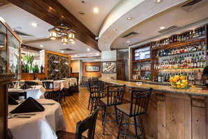 Bar featuring hardwood / wood-style floors and light stone countertops