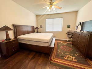 Bedroom featuring a textured ceiling, ceiling fan, and dark hardwood / wood-style floors