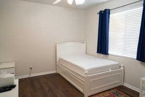 Bedroom featuring ceiling fan, dark hardwood / wood-style flooring, and multiple windows