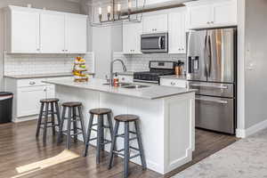 Kitchen featuring white cabinetry, a center island with sink, and appliances with stainless steel finishes